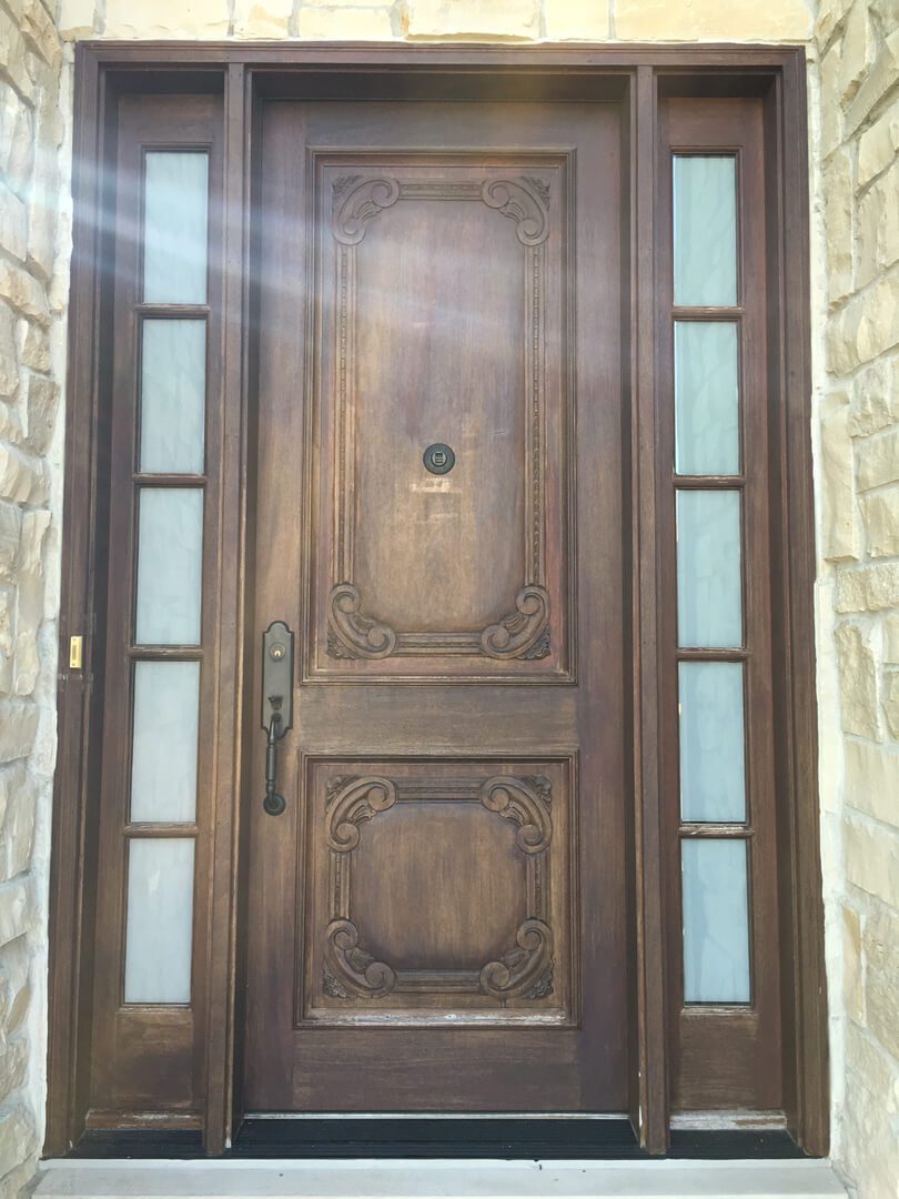 A wooden door with two glass panels on the side.
